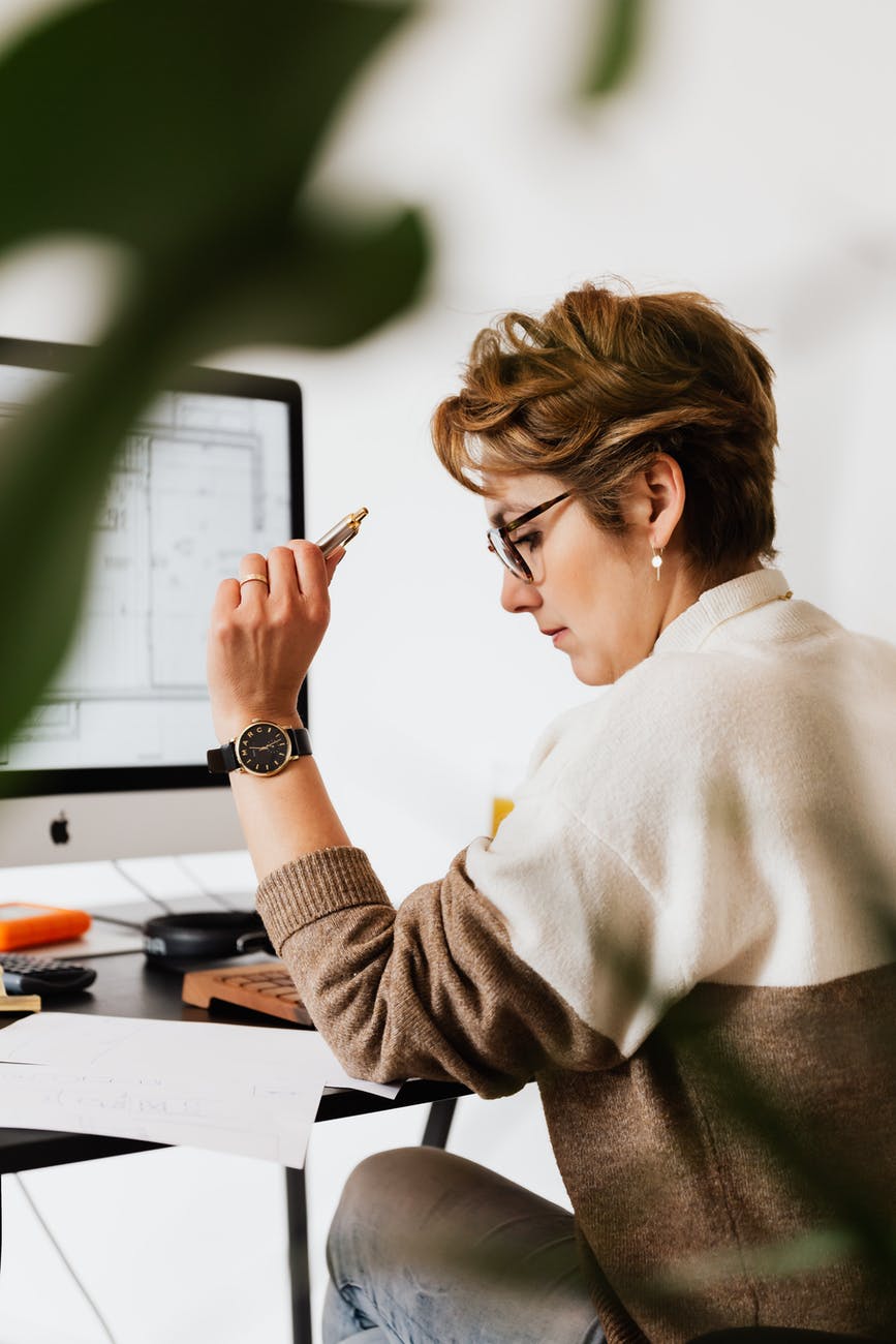 focused businesswoman reading documents and working on computer in office